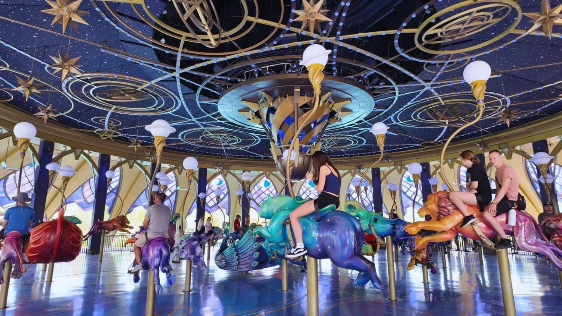 Colorful carousel at Disneyland, featuring ornate horses and vibrant lights, surrounded by excited visitors enjoying the ride.