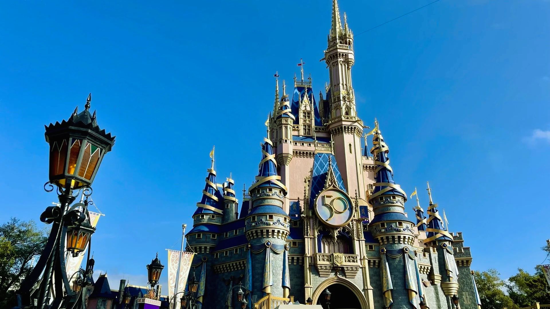 A blue Disney World castle featuring a prominent clock tower against a clear sky.