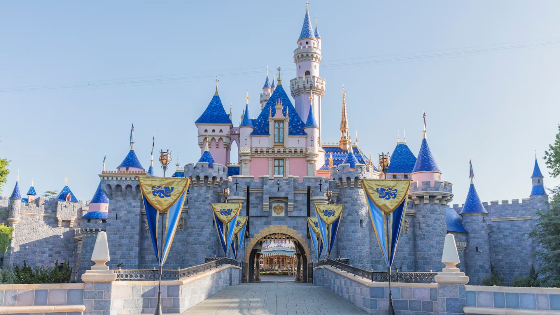Disneyland's castle adorned with blue and white flags, showcasing a whimsical fairytale atmosphere.