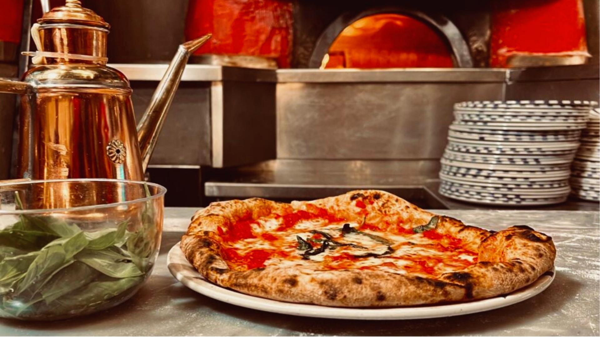 A pizza on a plate beside a shiny copper pot, showcasing a warm and inviting dining setting.