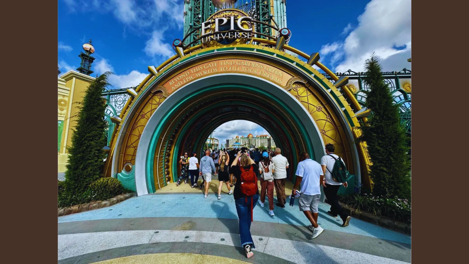 A group of people entering an amusement park through a colorful archway, excited for a day of fun and entertainment.