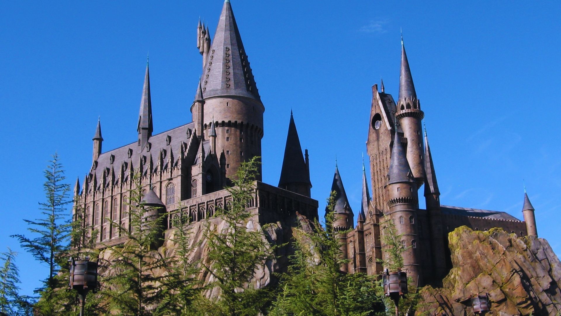 Hogwarts Castle stands majestically in the background, showcasing its iconic towers and turrets against a clear sky.