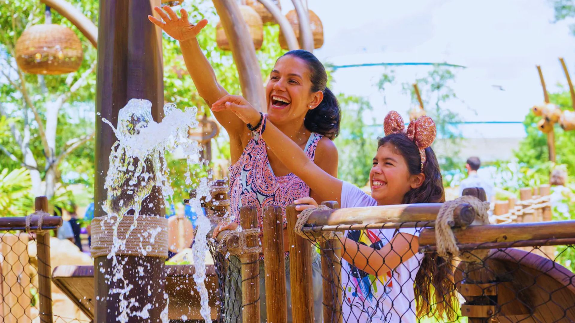Two girls joyfully splashing in the water at a vibrant water park, surrounded by colorful slides and attractions.