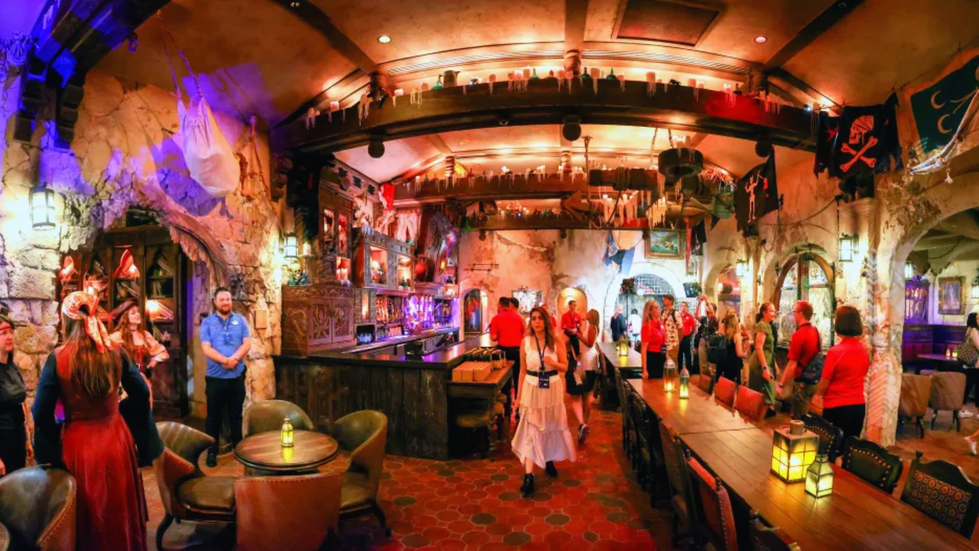 A group of people stands together in a lively bar, engaging in conversation and enjoying their drinks.