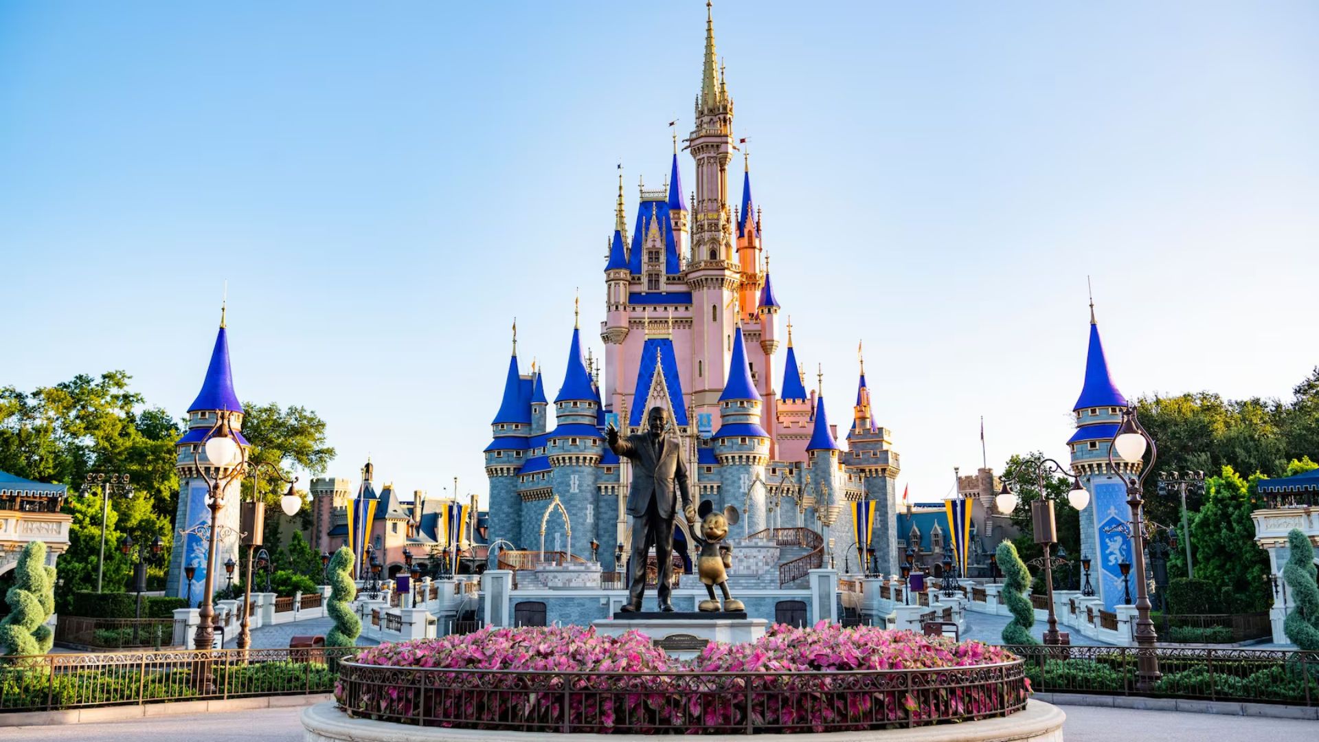 Cinderella Castle at Disney World, a majestic fairytale structure with spires, surrounded by vibrant gardens and blue skies.