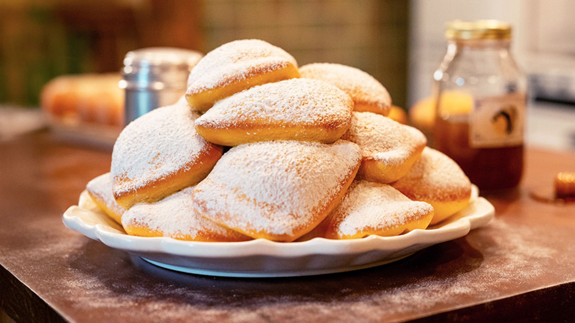 A plate of pastries dusted with powdered sugar sits on a table, invitingly arranged for dessert.