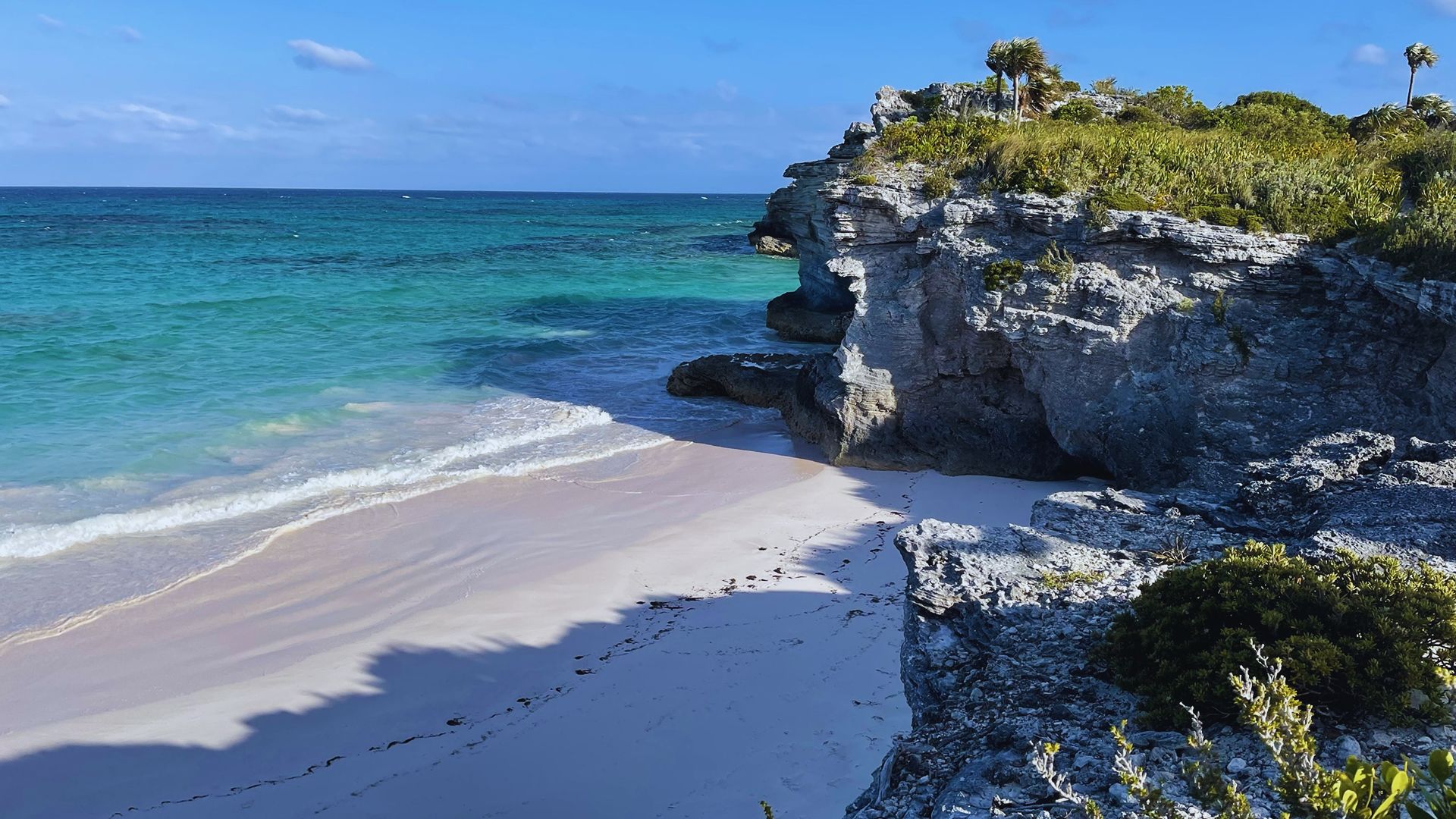 A scenic view of Tulum beach in Mexico, featuring soft white sand and turquoise waters under a clear blue sky.