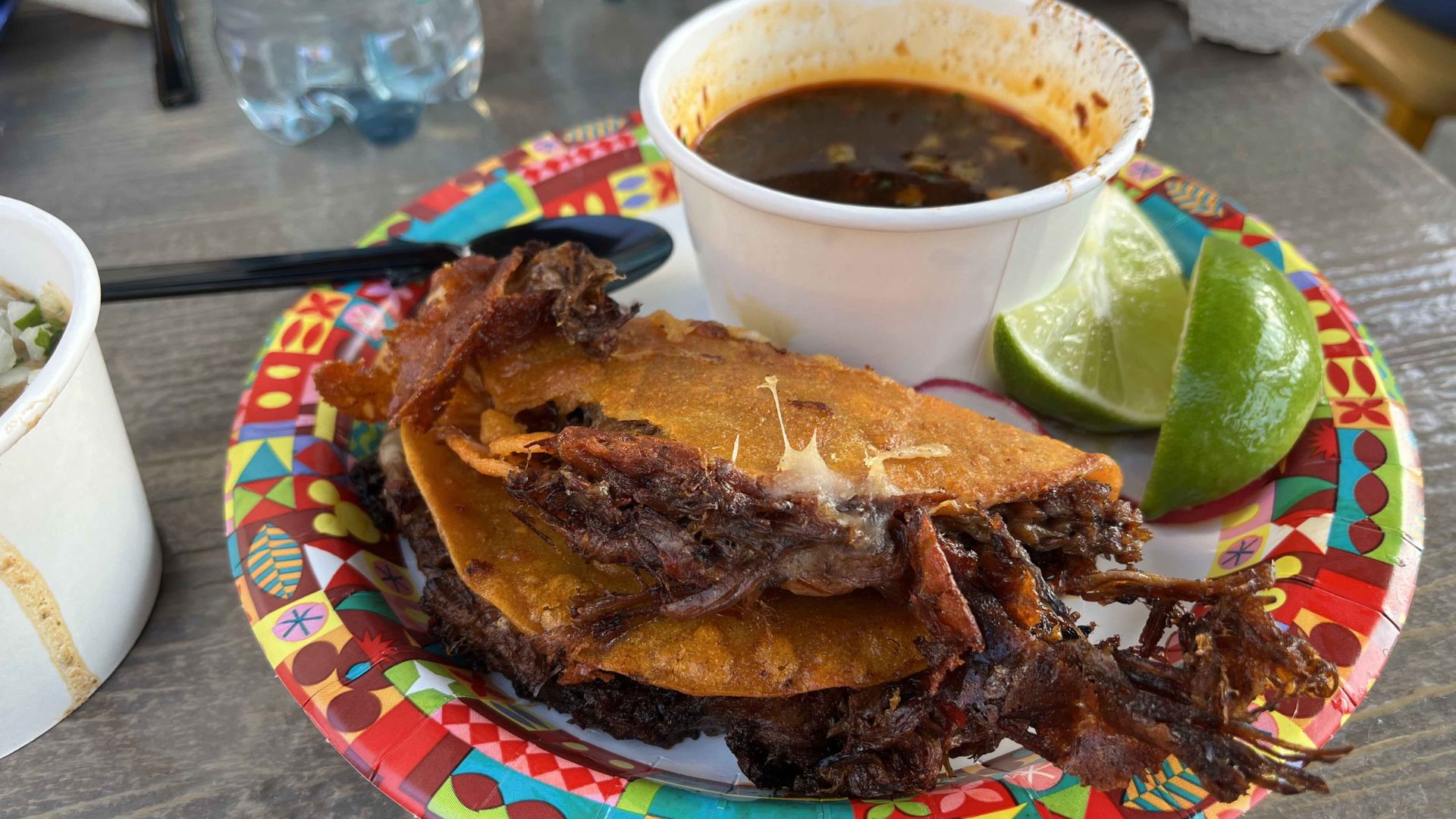 A plate of meat accompanied by a cup of soup, arranged neatly on a dining table.