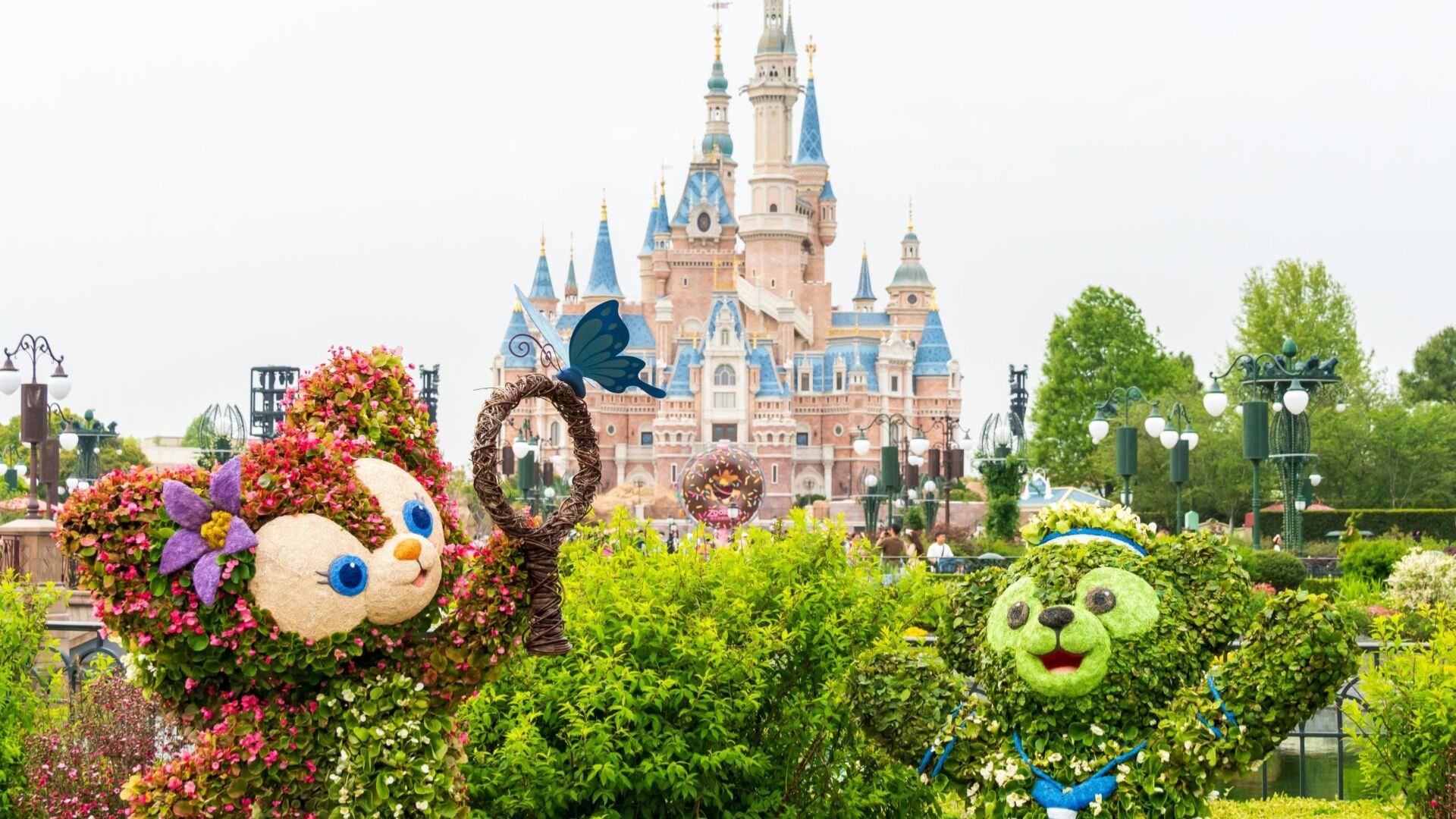 Lush topiary garden at Disneyland featuring intricately shaped bushes and vibrant flowers under a clear blue sky.
