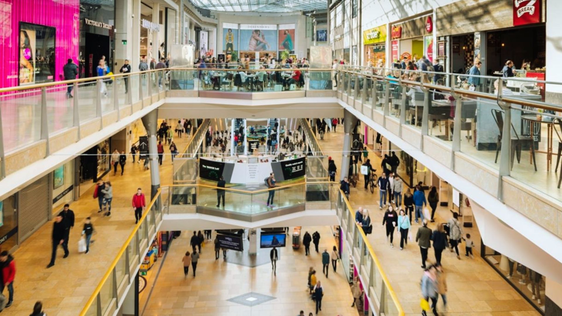 A vibrant shopping mall with crowds of people strolling and exploring various shops.