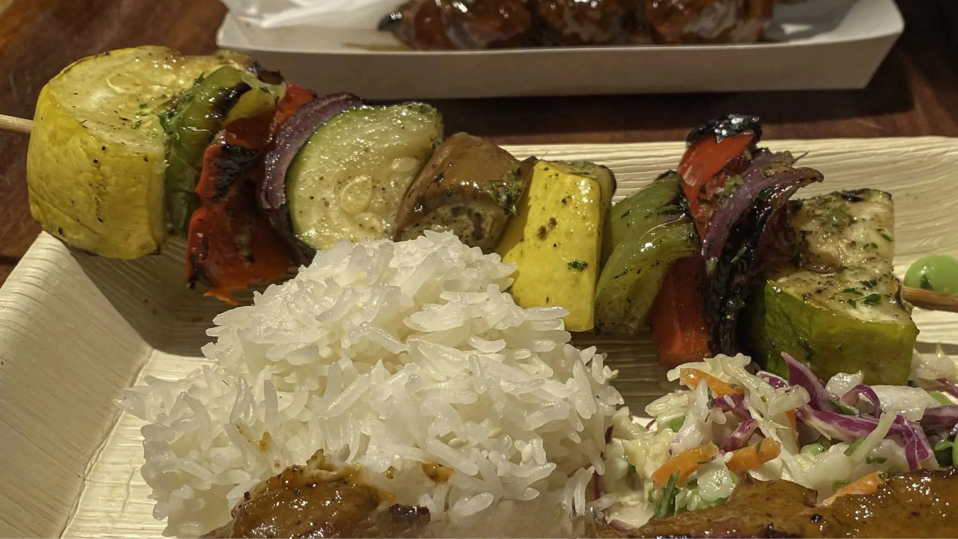 A plate featuring rice accompanied by colorful skewers of grilled vegetables.