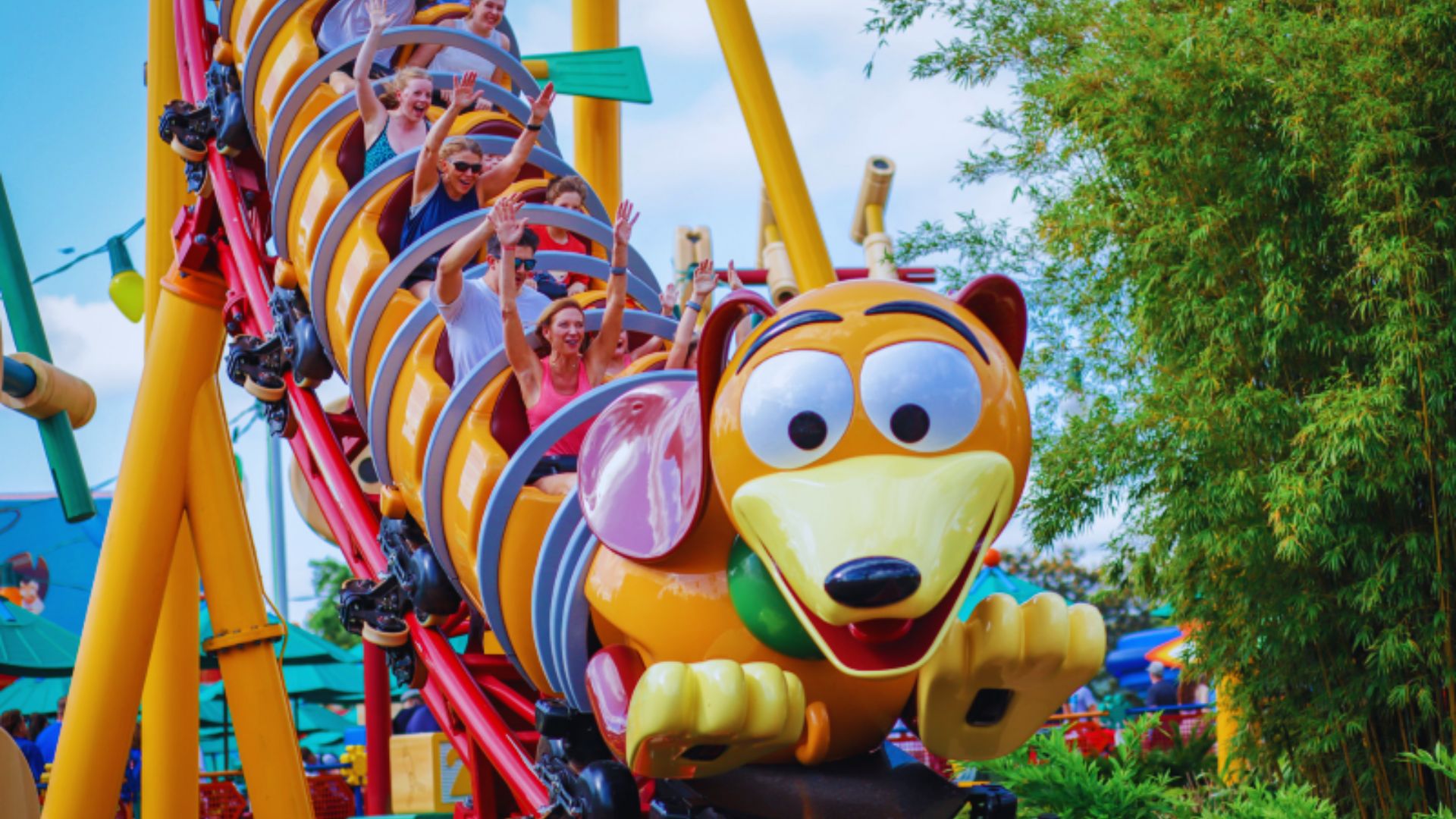 A vibrant yellow and orange roller coaster with a dog sitting in one of the cars, enjoying the ride.