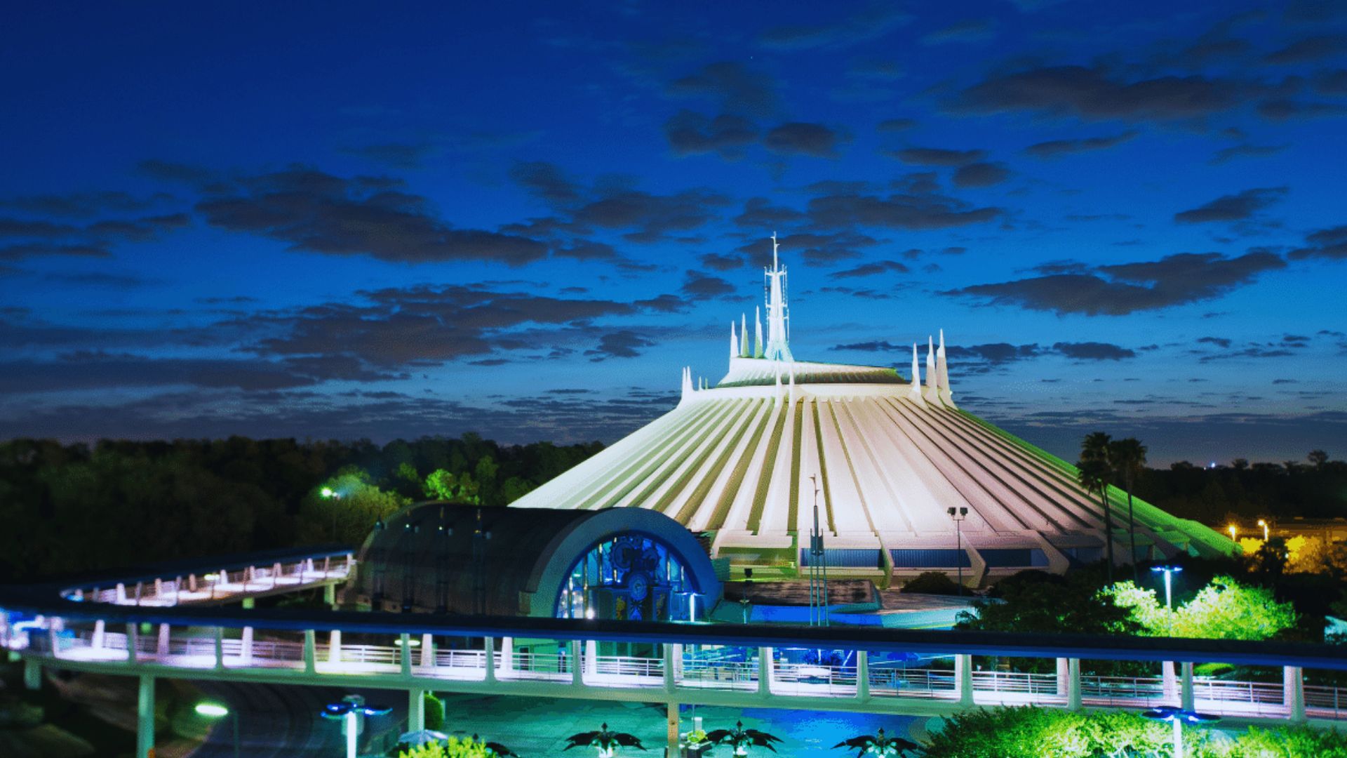 Space Mountain illuminated at night, showcasing its sleek design against a dark sky filled with stars.