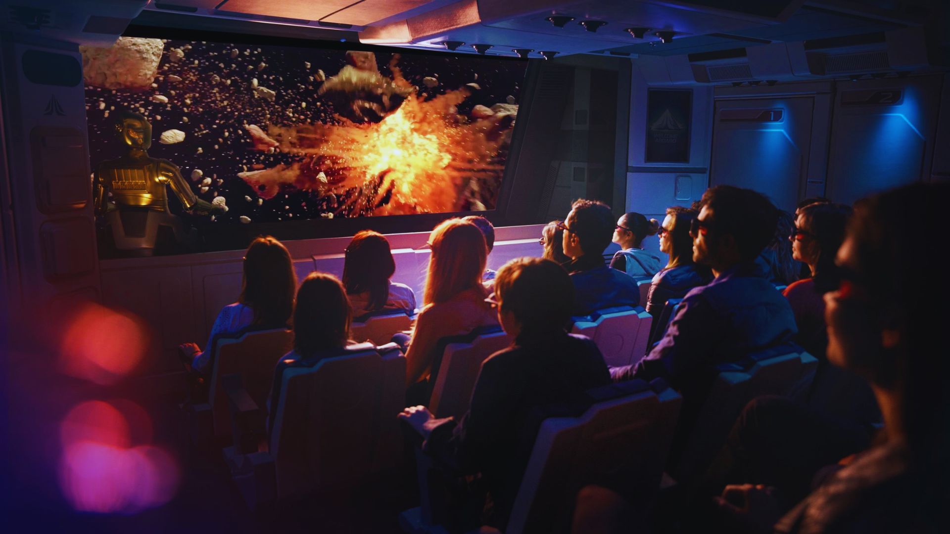 A group of people seated in a dark theater, focused on a large movie screen displaying a film.