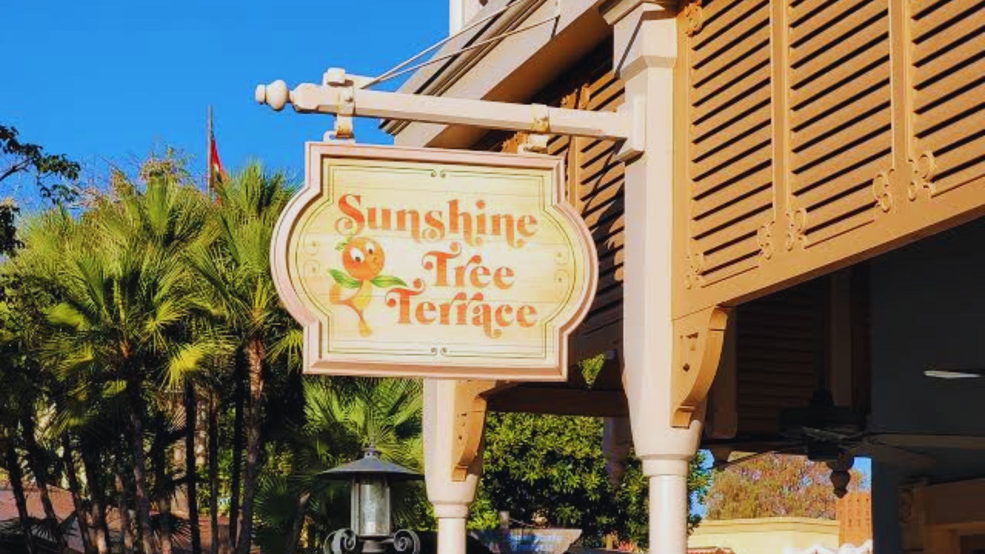 A sign for Sunshine Tree Tea hangs on the side of a building, featuring a bright design and inviting text.