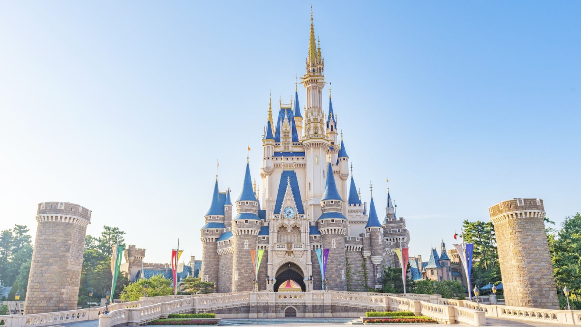 Cinderella Castle at Disney World, a majestic fairytale structure with spires, surrounded by vibrant gardens and blue skies.