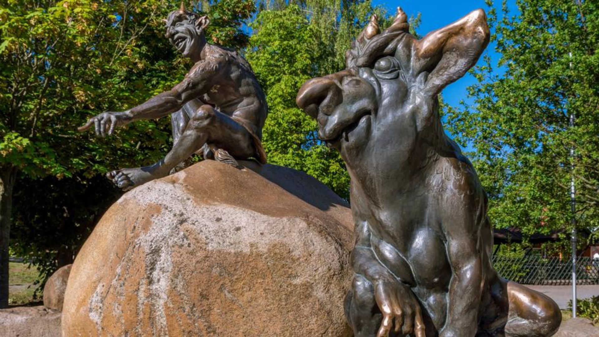 A statue depicting two goats sitting together on a rock, showcasing their playful and serene nature.