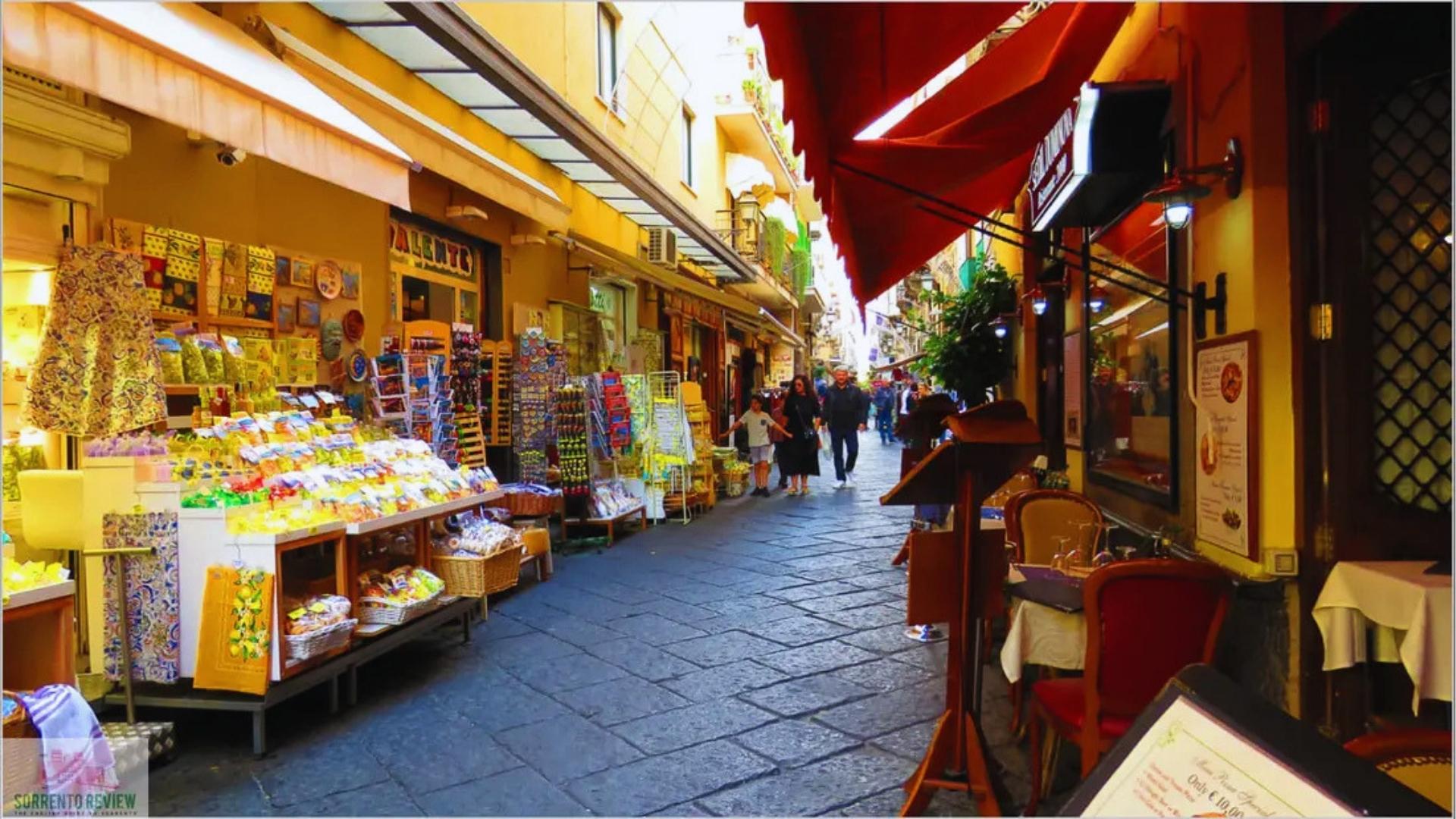 A narrow street bustling with people walking and shops lining both sides, creating a lively urban atmosphere.
