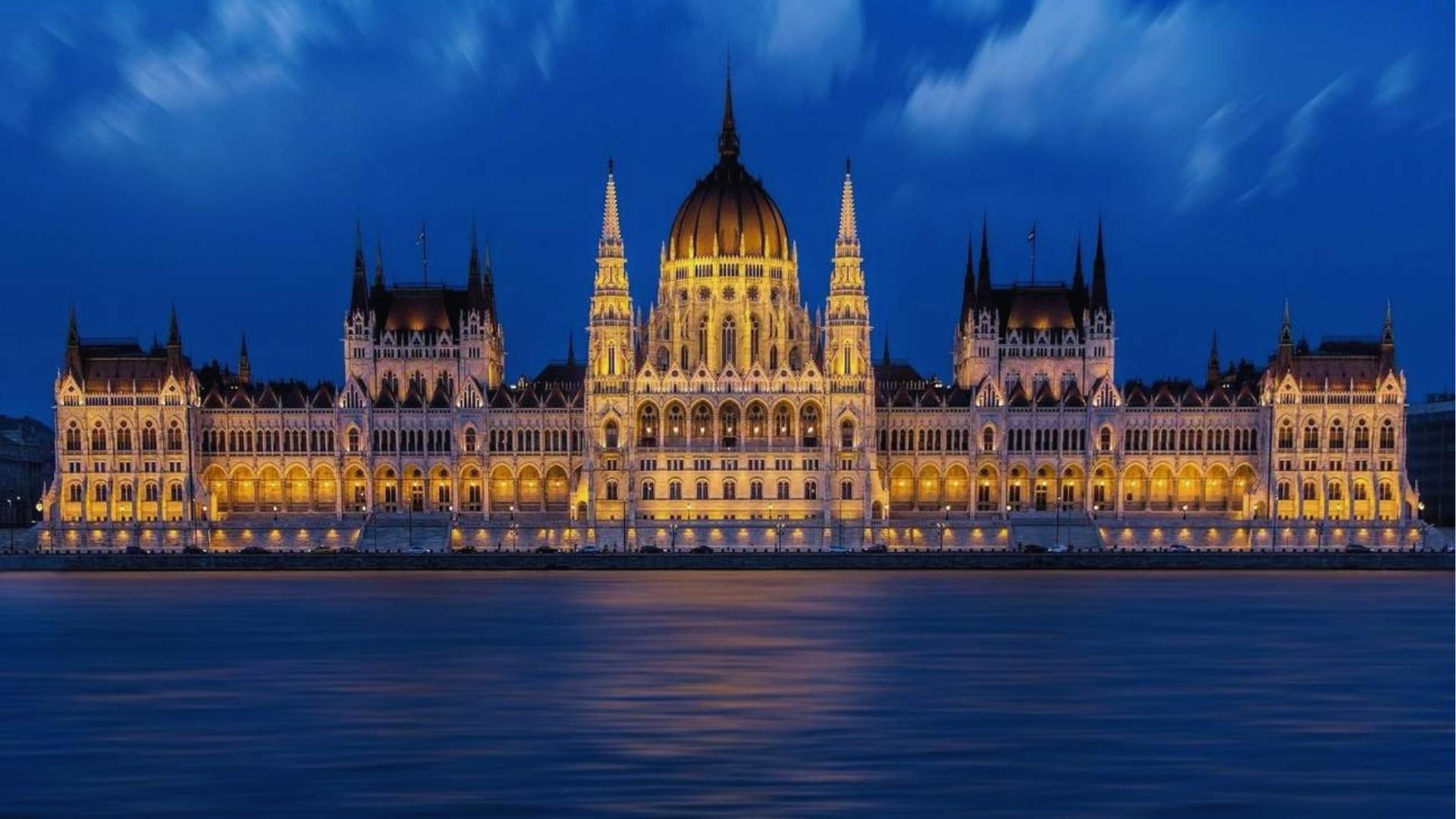 The Hungarian Parliament Building illuminated at night, showcasing its stunning architecture against a dark sky.