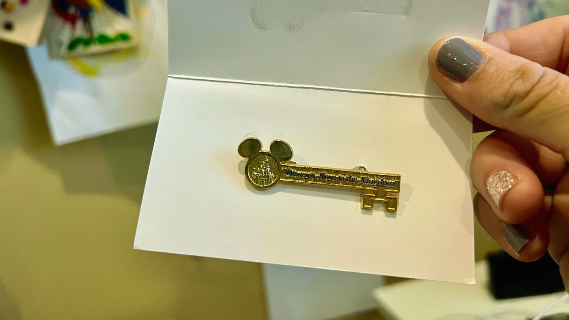 A person holds a key featuring a Mickey Mouse design, showcasing a playful and whimsical accessory.