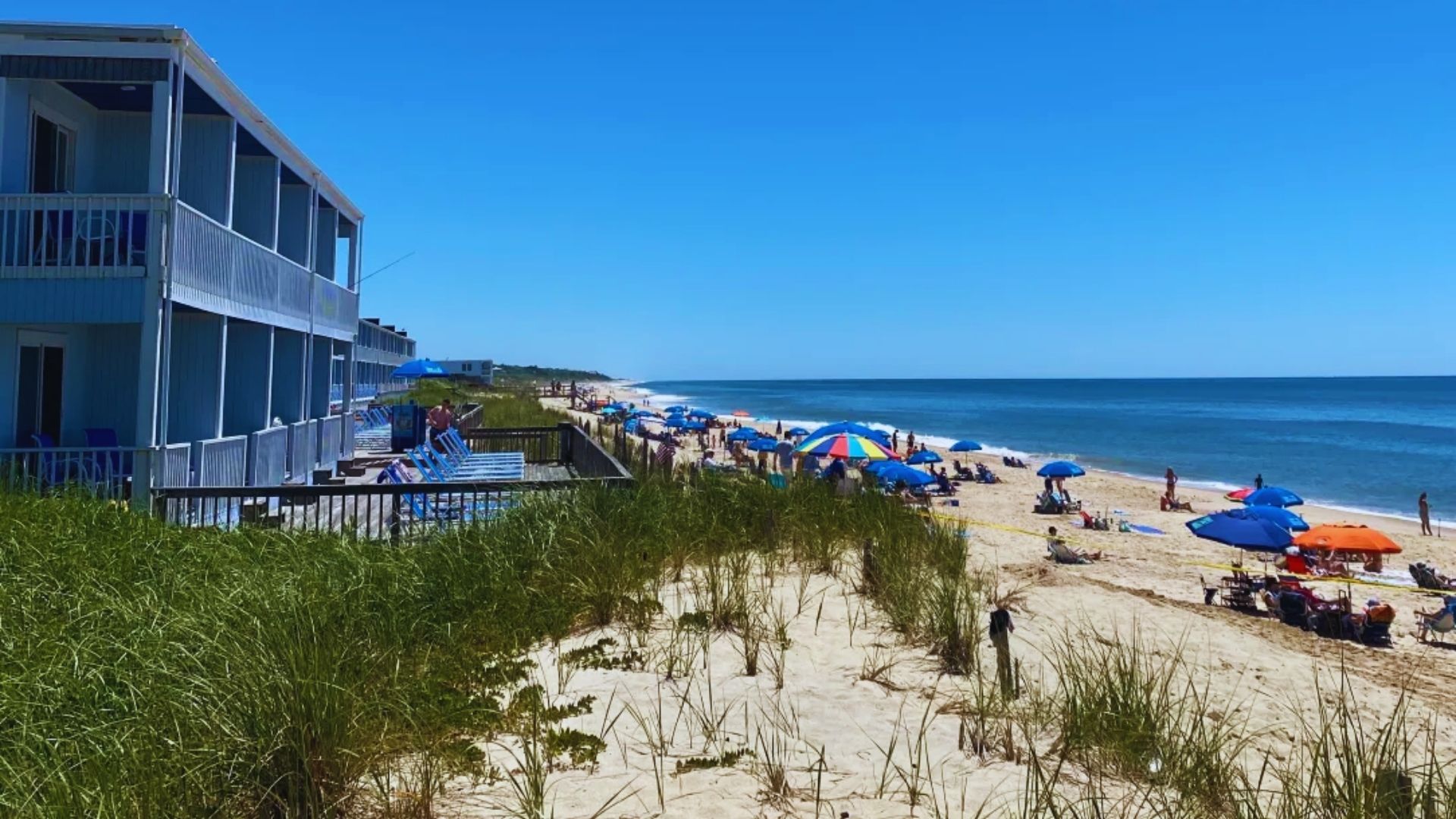 A crowded beach filled with people enjoying the sun, surrounded by colorful umbrellas providing shade.