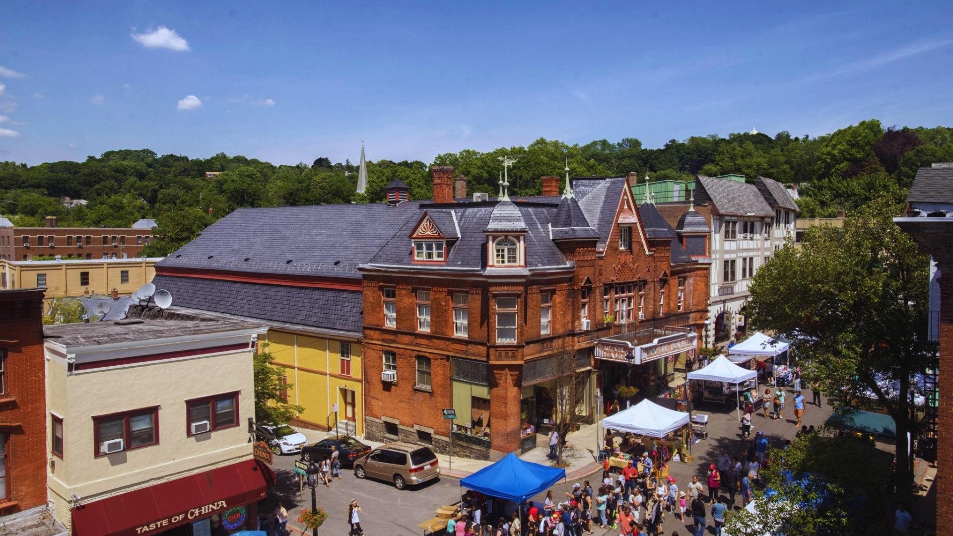 A bustling town square filled with people walking and socializing under clear blue skies.