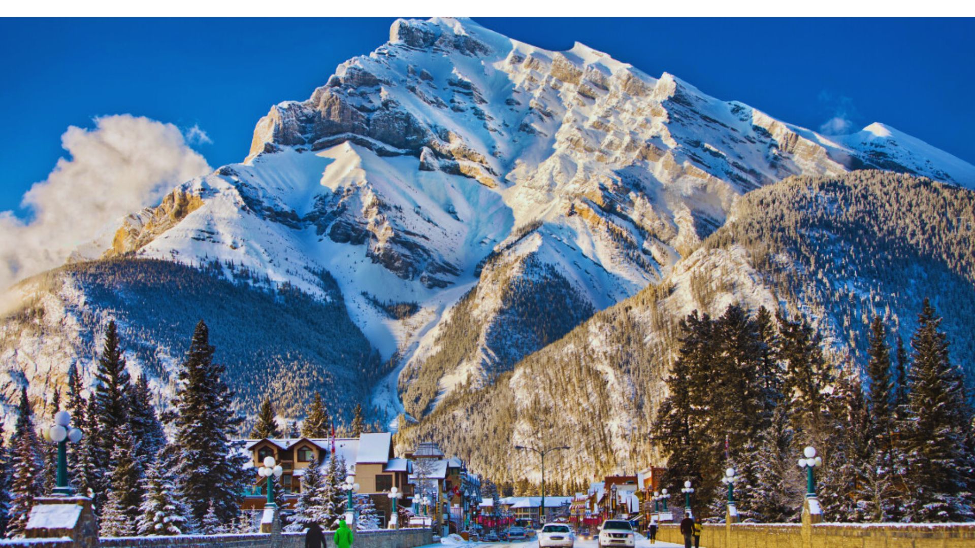 A snowy mountain rises in the background, with a winding road leading towards it in the foreground.
