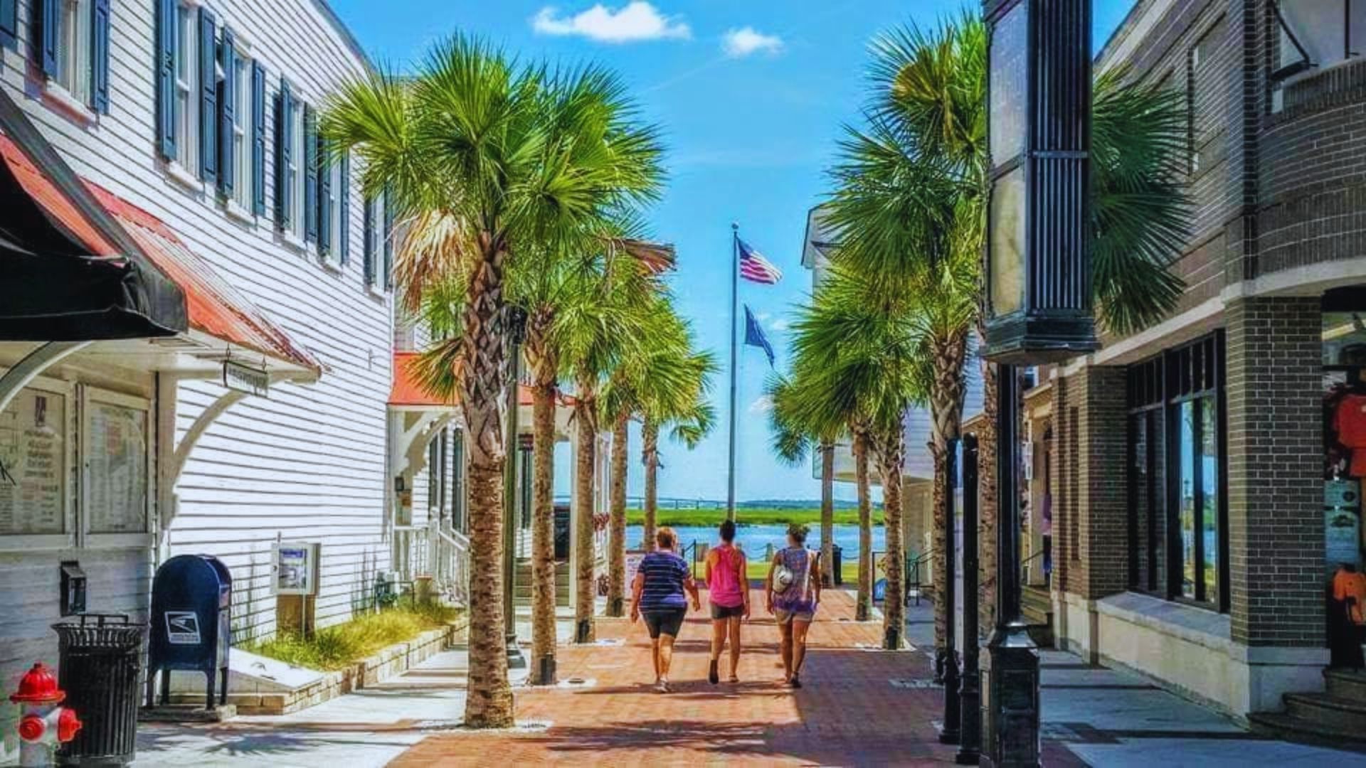 A group of individuals walks down a brick path in front of various shops, showcasing a lively shopping district.