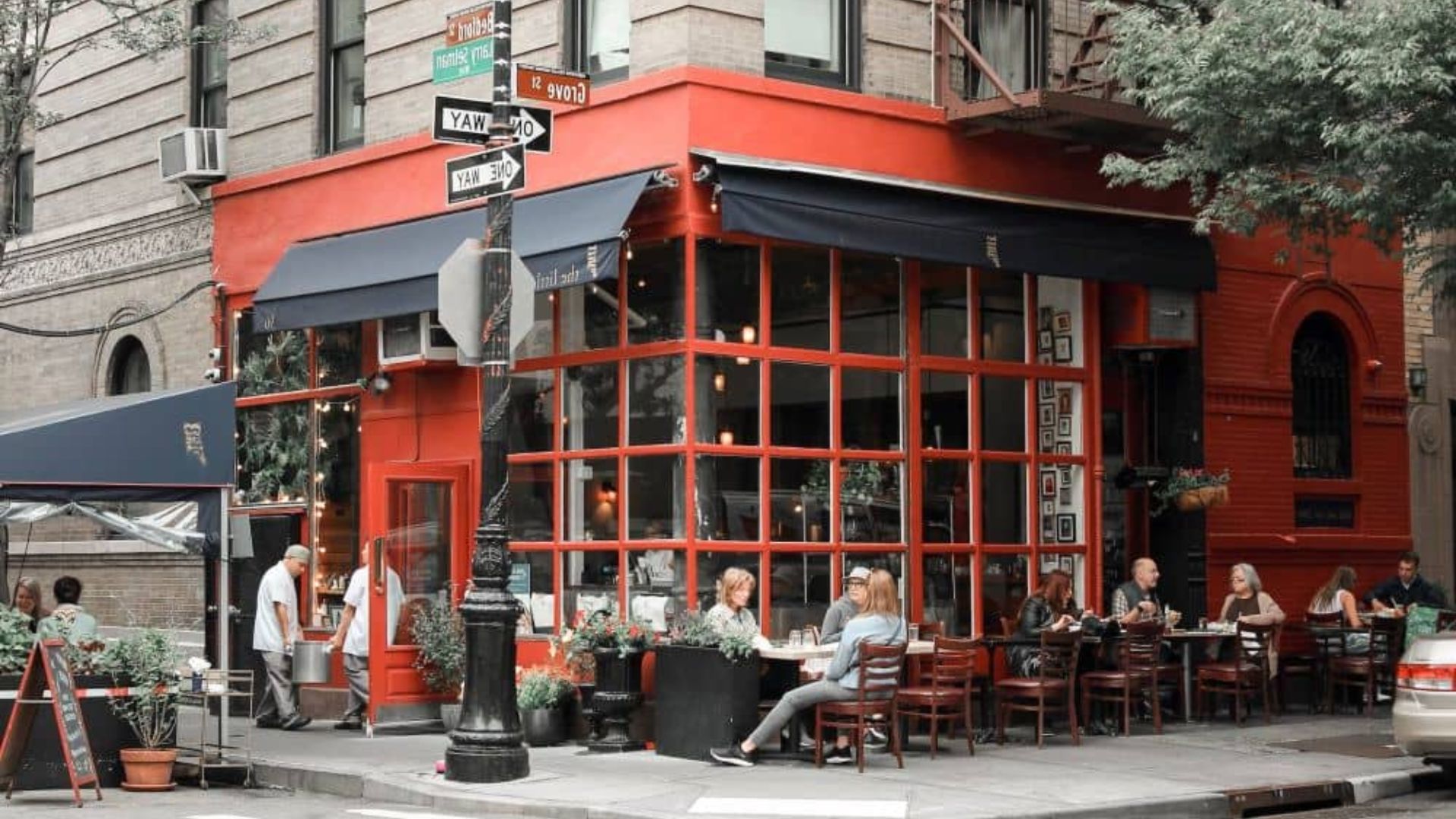A vibrant red restaurant with patrons dining outside on a sunny day.