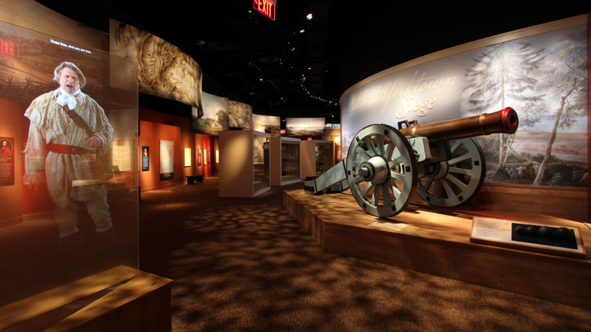 A museum exhibit featuring a historical cannon alongside a man in a suit, highlighting military history.