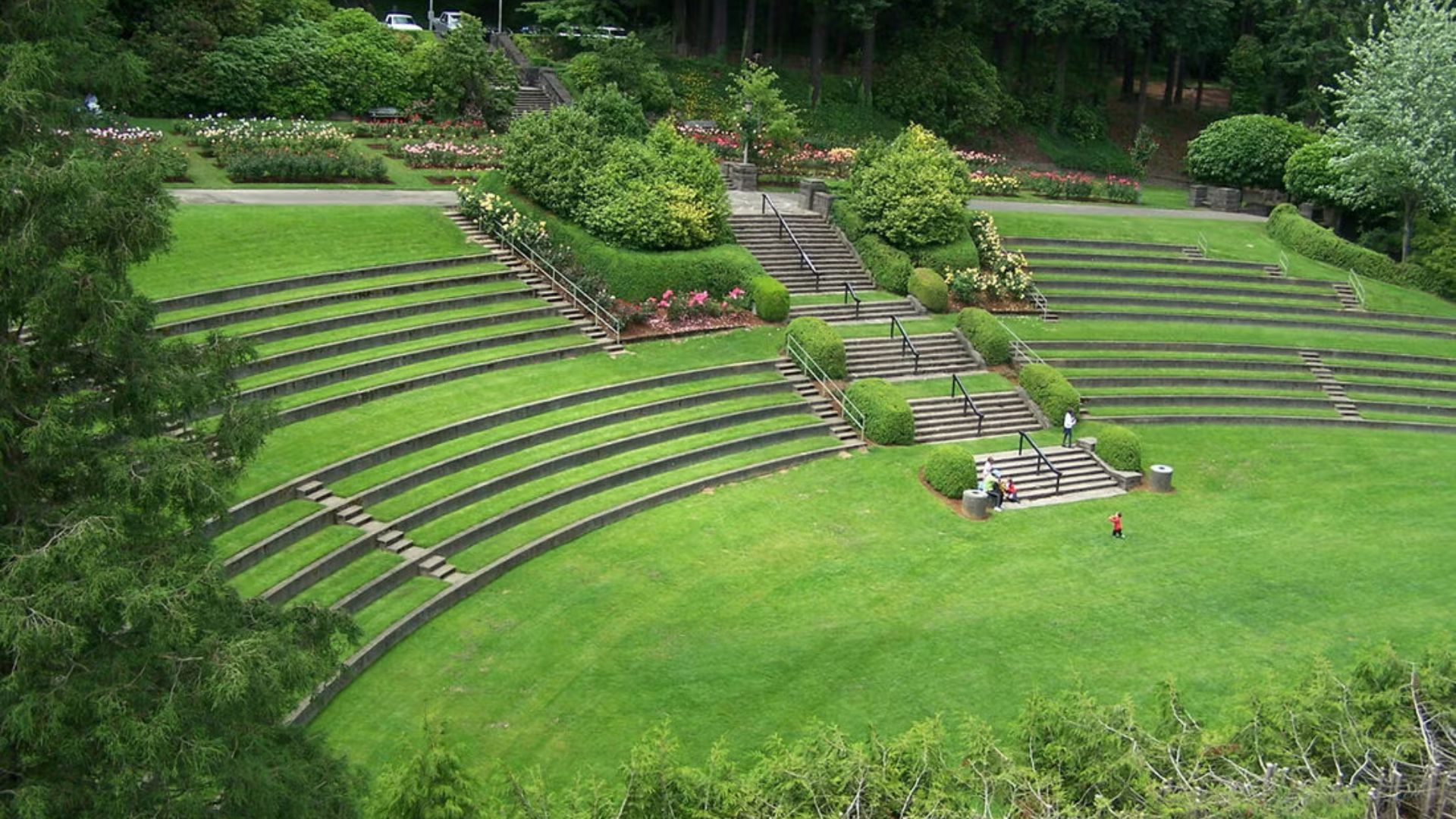 An outdoor amphitheater featuring a spacious lawn and tiered seating stairs for audience viewing.