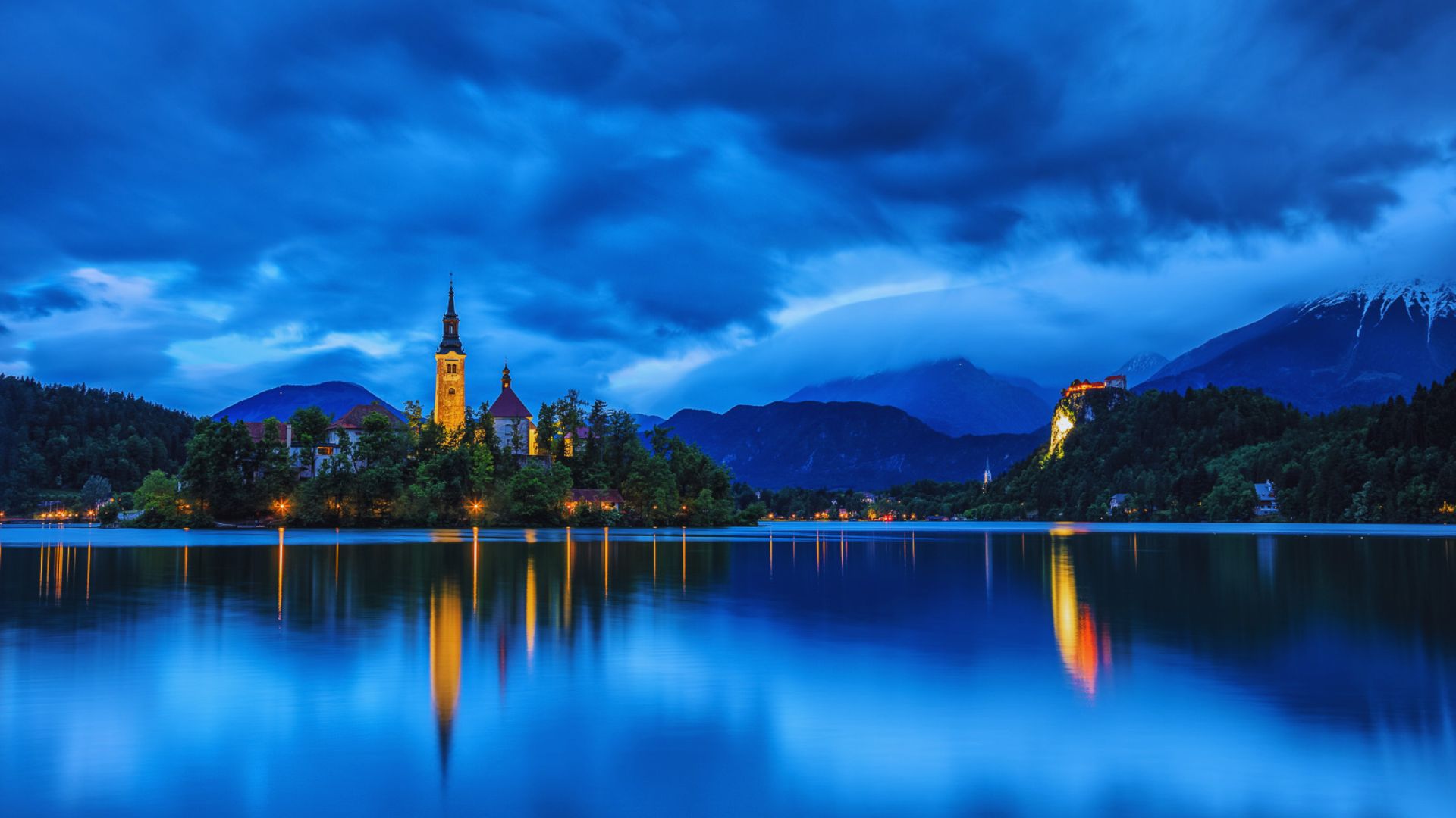 Scenic view of Lake Bled in Slovenia, featuring a church on an island and mountains in the background.