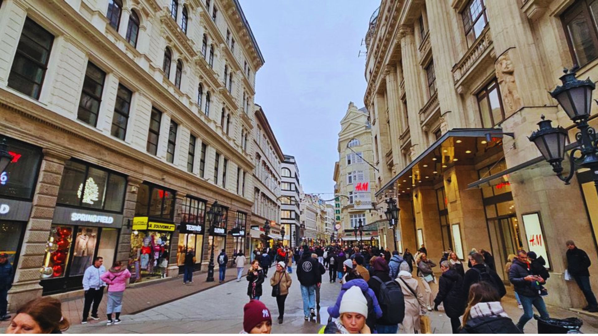 A bustling street filled with numerous people walking in various directions.