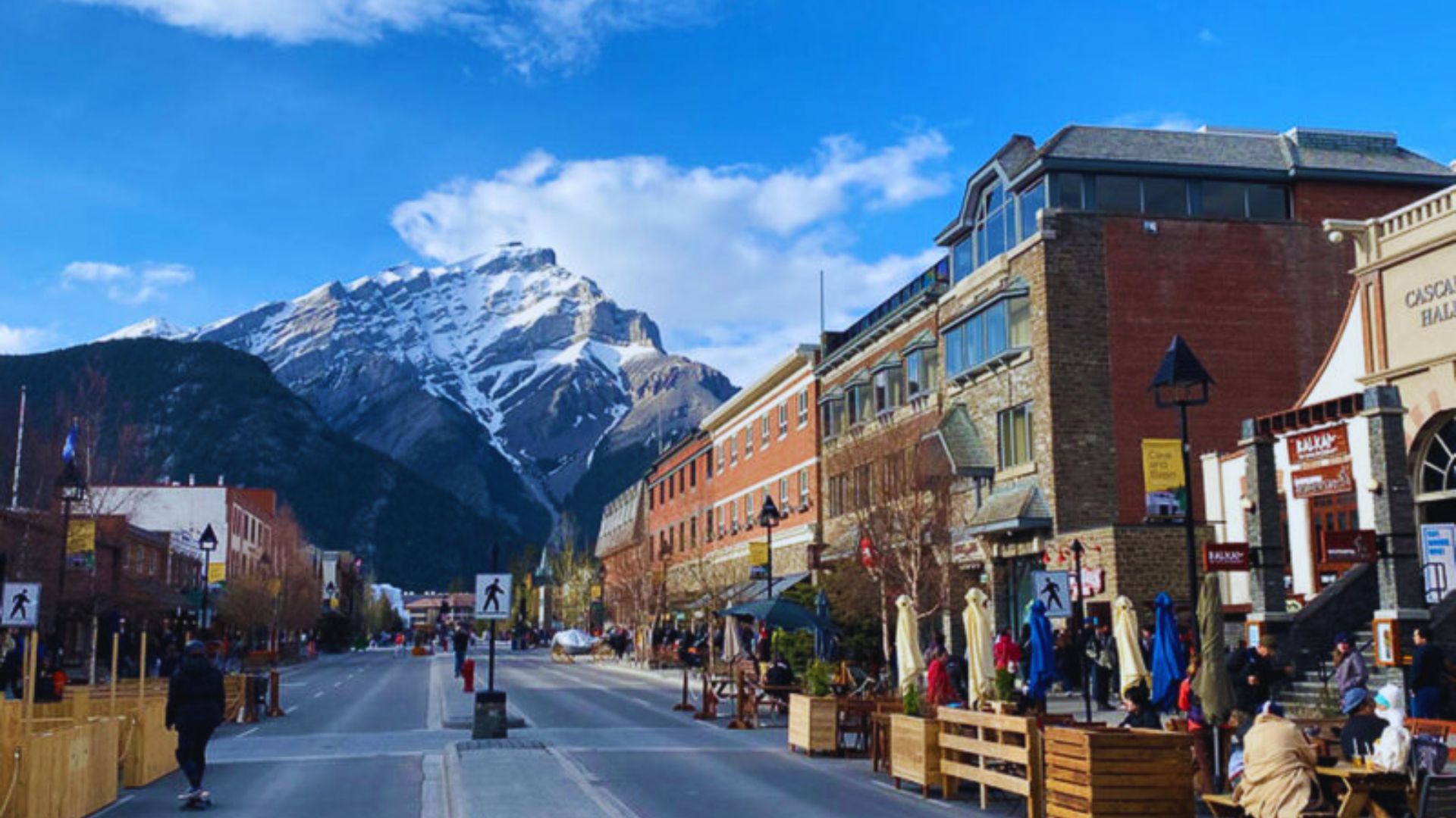 The town of Banff features a vibrant street lined with various shops and restaurants amidst scenic mountain views.