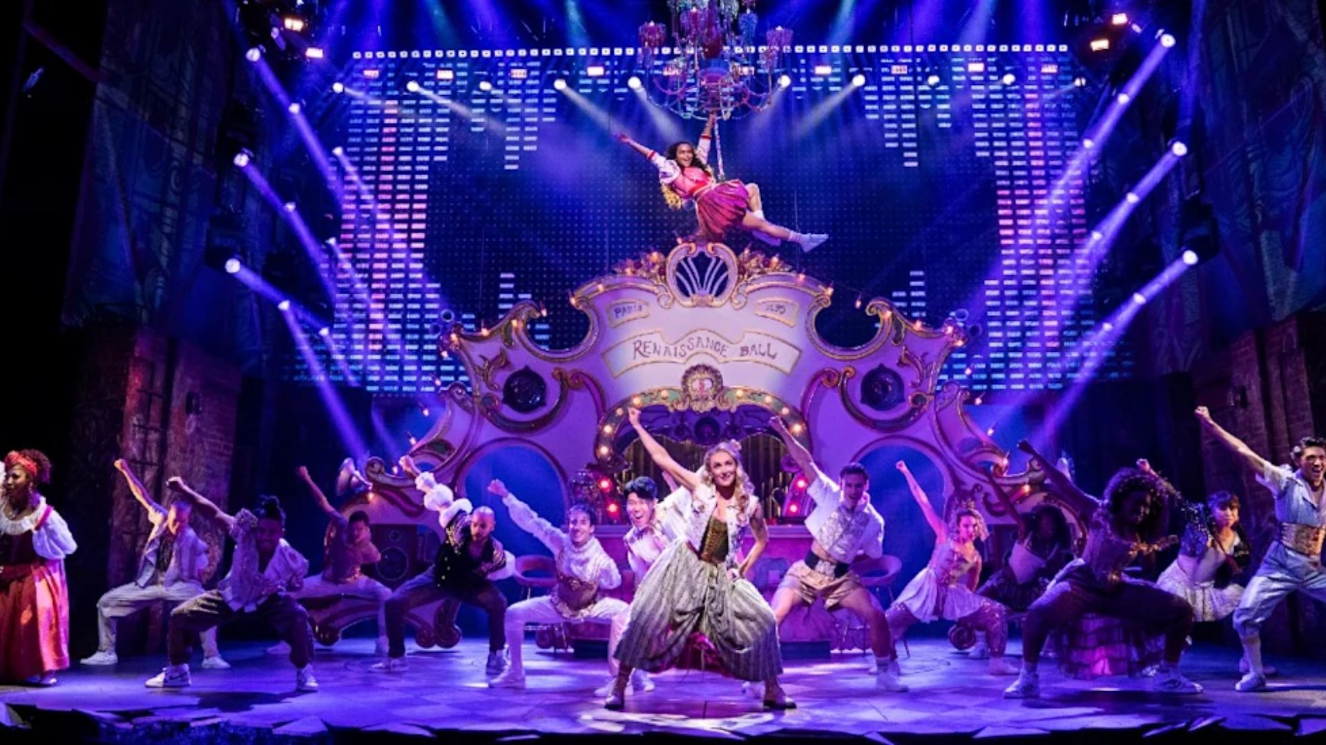 The cast of the musical production poses together, showcasing their costumes and expressions in a vibrant group photo.
