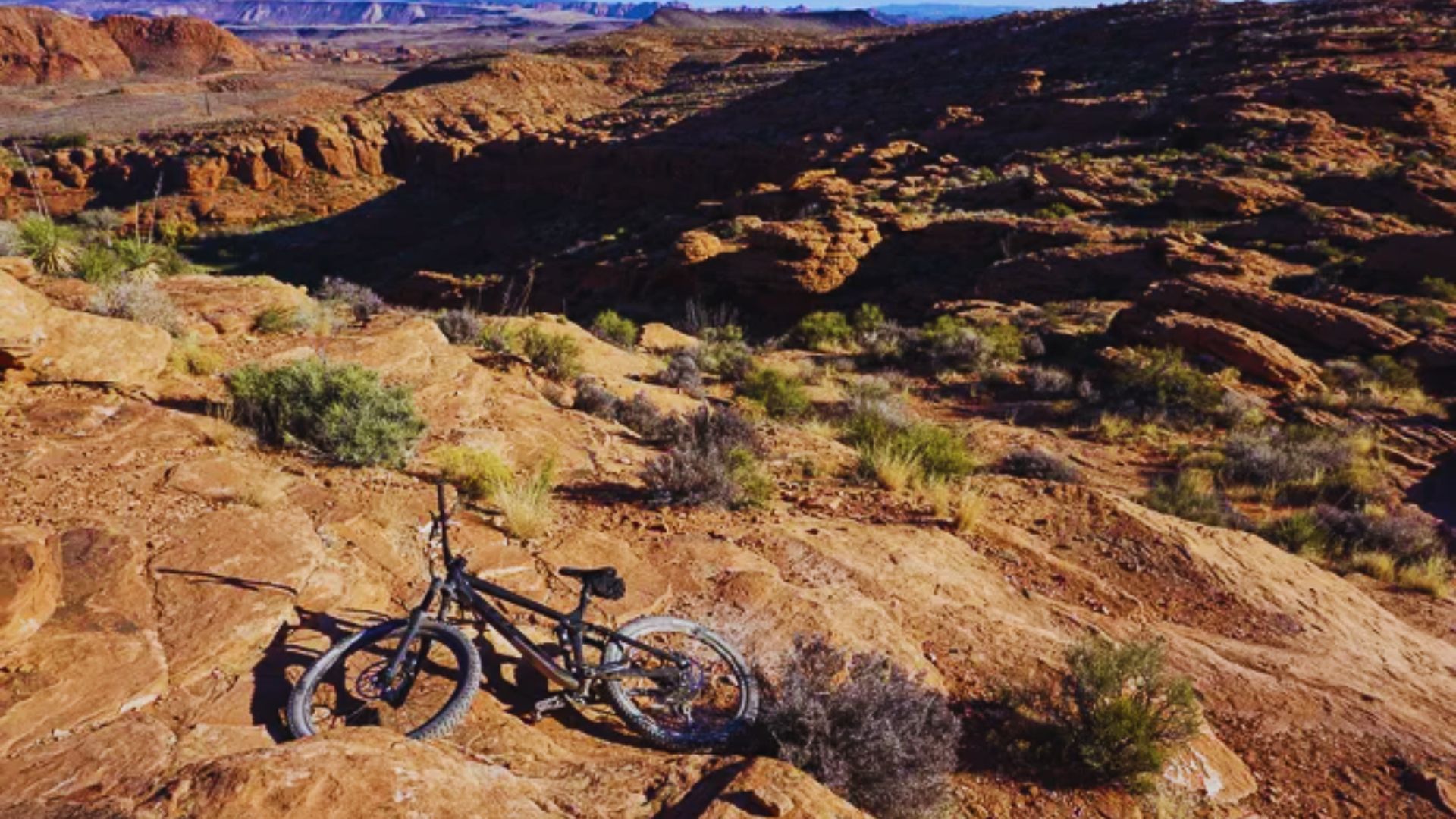 A bike is parked on a rocky hillside, surrounded by natural terrain and scattered stones.