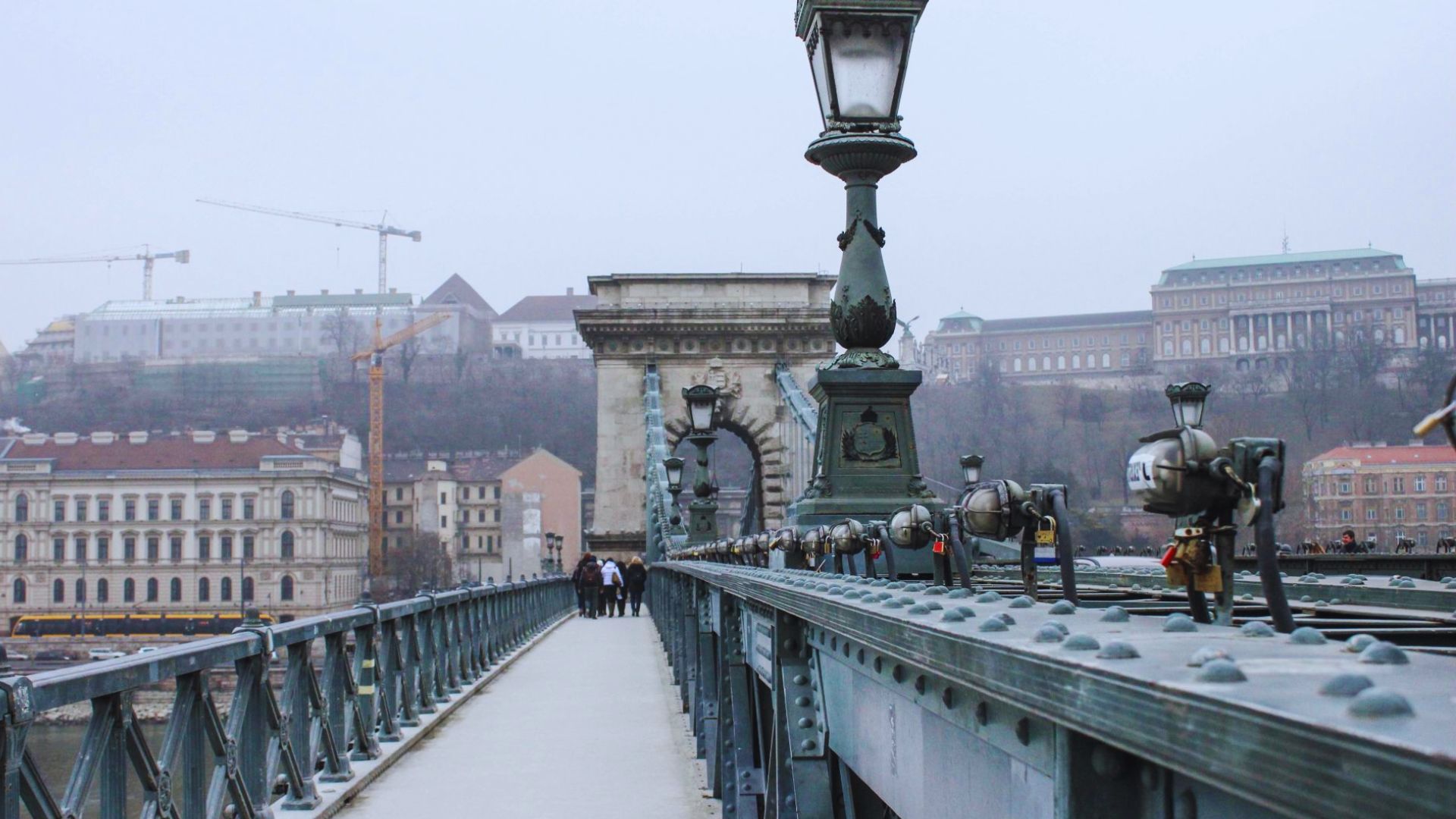 A busy bridge filled with numerous pedestrians walking in various directions under a clear blue sky.