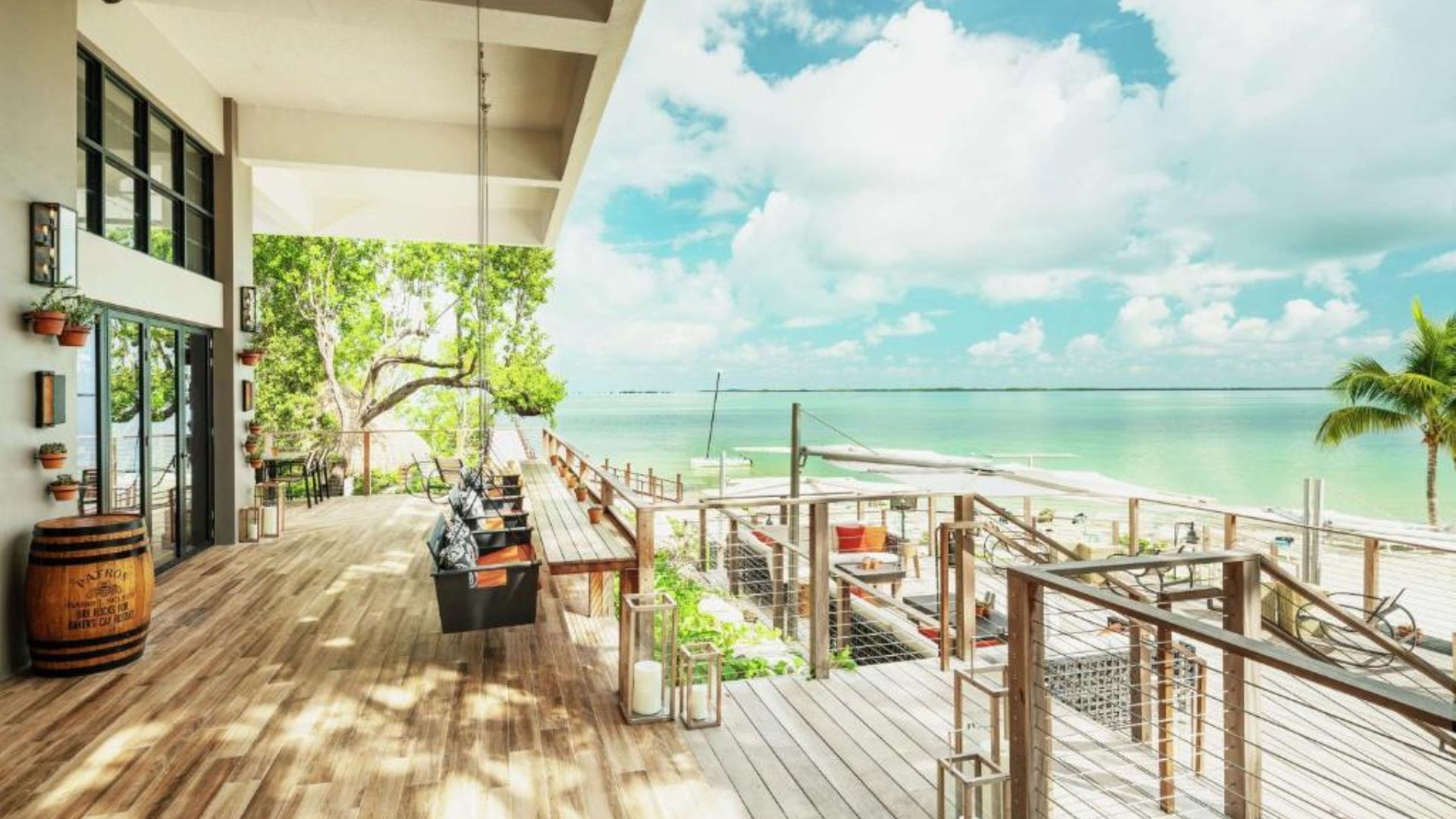 A beach house at the beach club, featuring a wooden deck and ocean views under a clear blue sky.