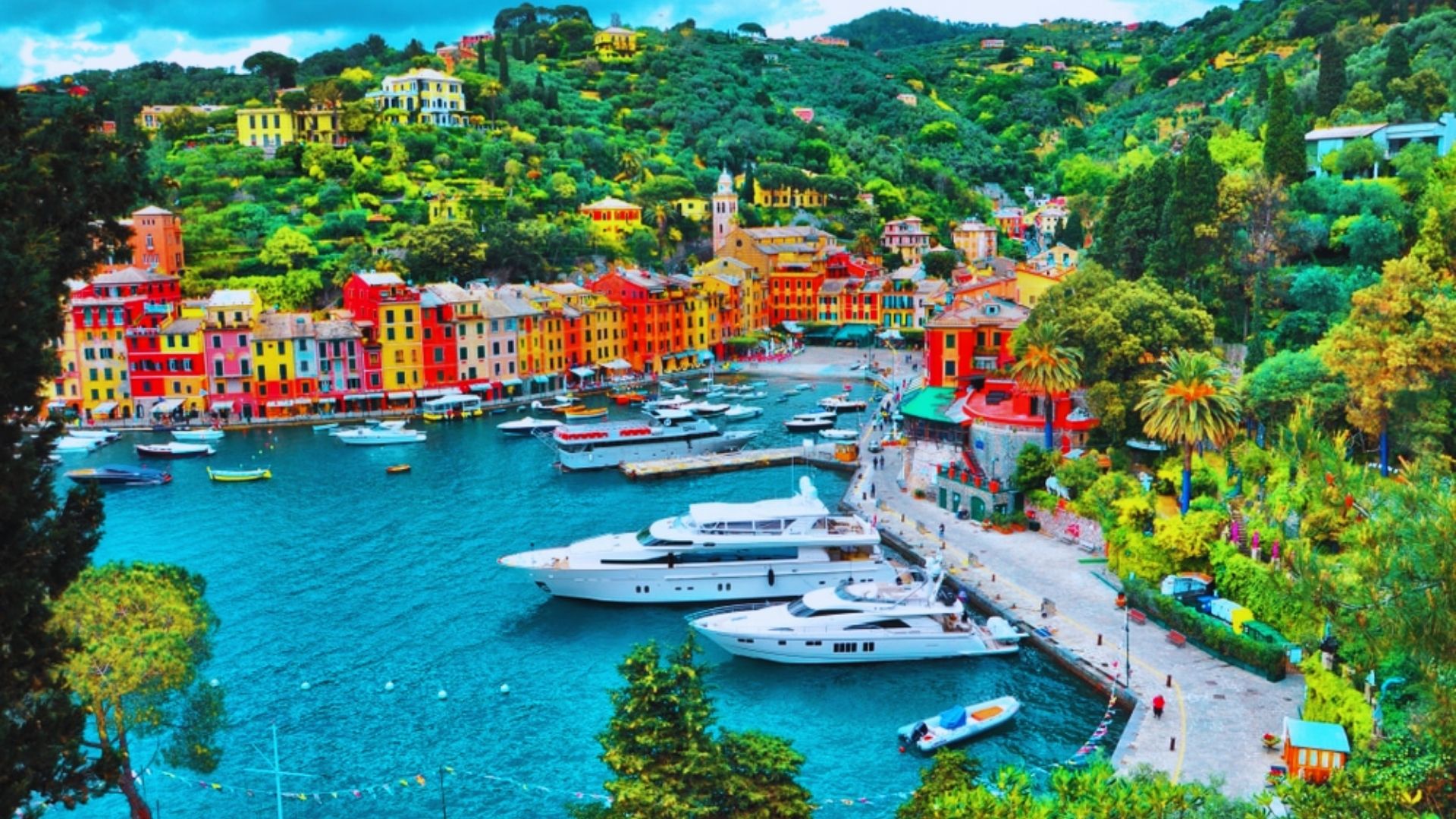 A picturesque landscape of Portofino, Italy, featuring vibrant waterfront buildings, moored boats, and surrounding hills.