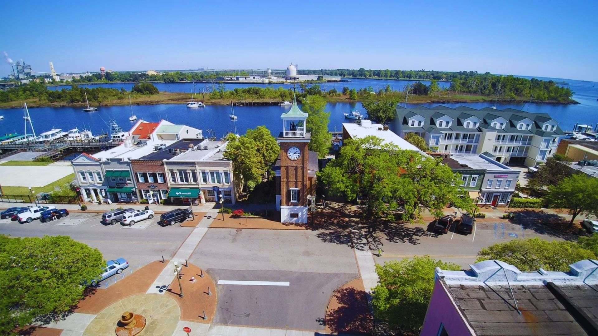 Aerial view of a town featuring a prominent clock tower amidst residential and commercial buildings.