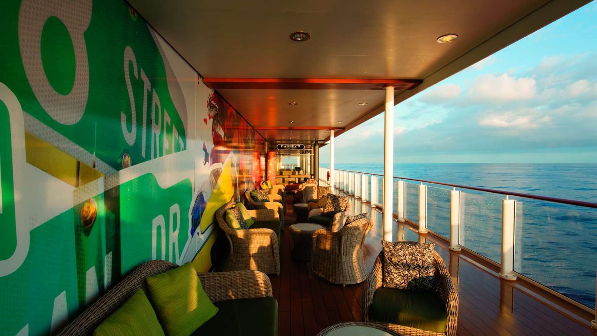 A cruise ship deck featuring wicker furniture and a vibrant mural, creating a relaxing outdoor atmosphere.