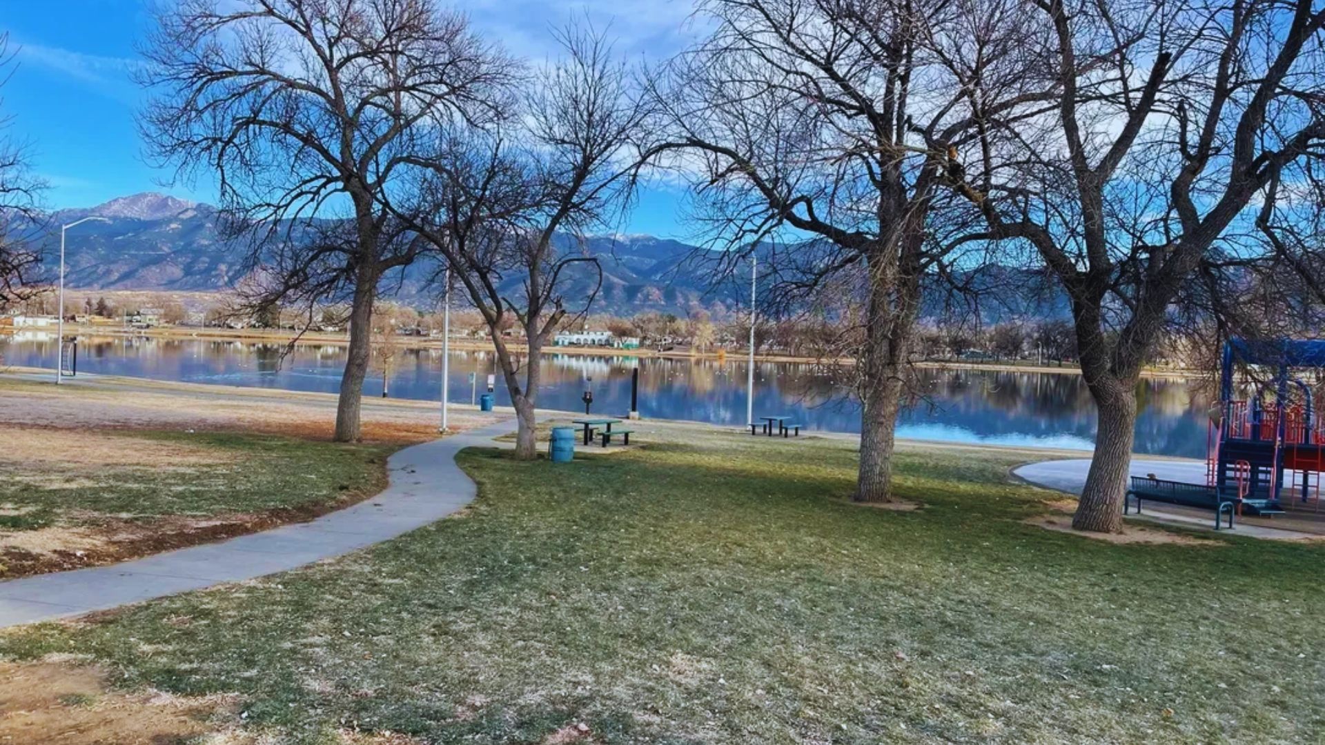 A scenic park featuring a tranquil lake and a vibrant playground area for children to enjoy.