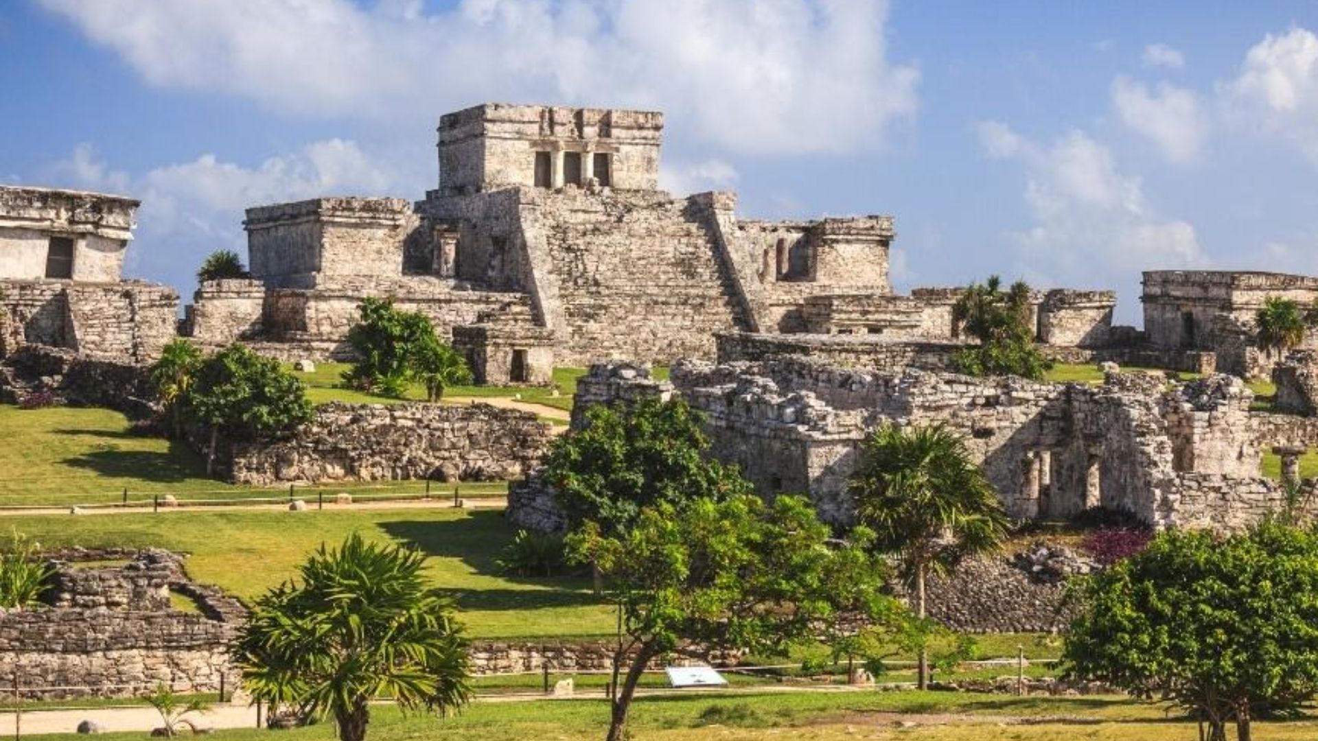 The ancient ruins of Tulum, Mexico, showcasing stone structures against a clear blue sky and lush greenery.