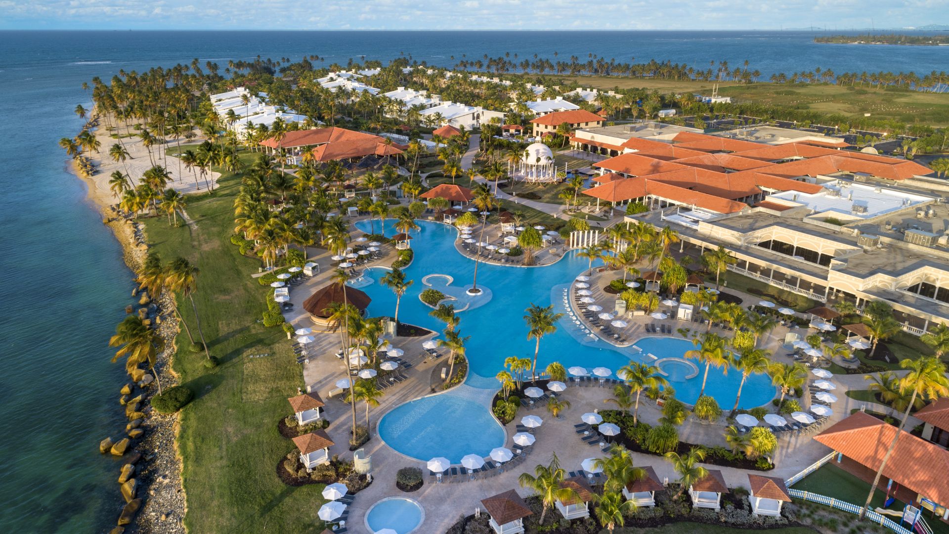 A tropical resort bordered by swaying palm trees and clear water, providing a relaxing and scenic getaway.