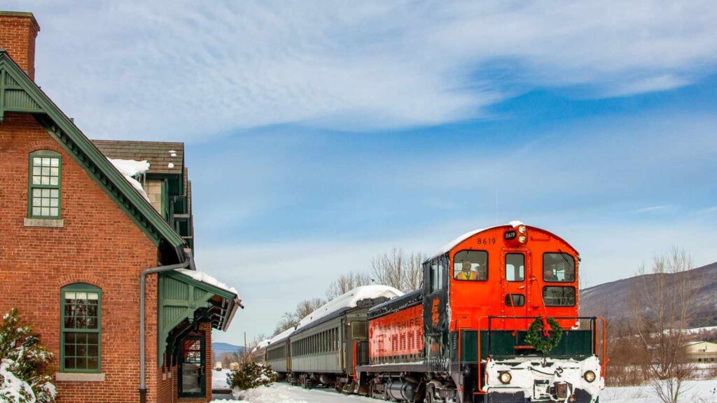 A red and black train moves along a snowy track, surrounded by a winter landscape.