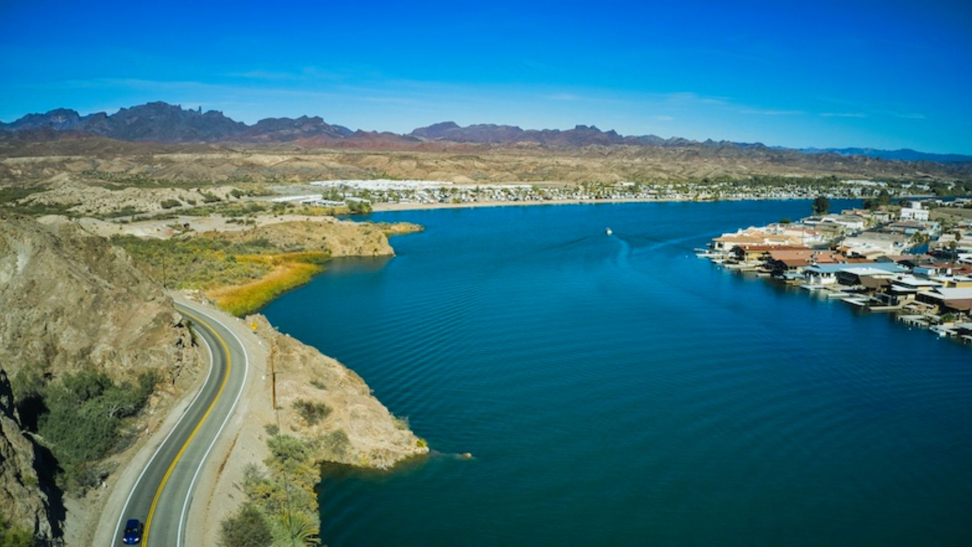 A scenic view of a river flowing through a town, surrounded by majestic mountains in the background.