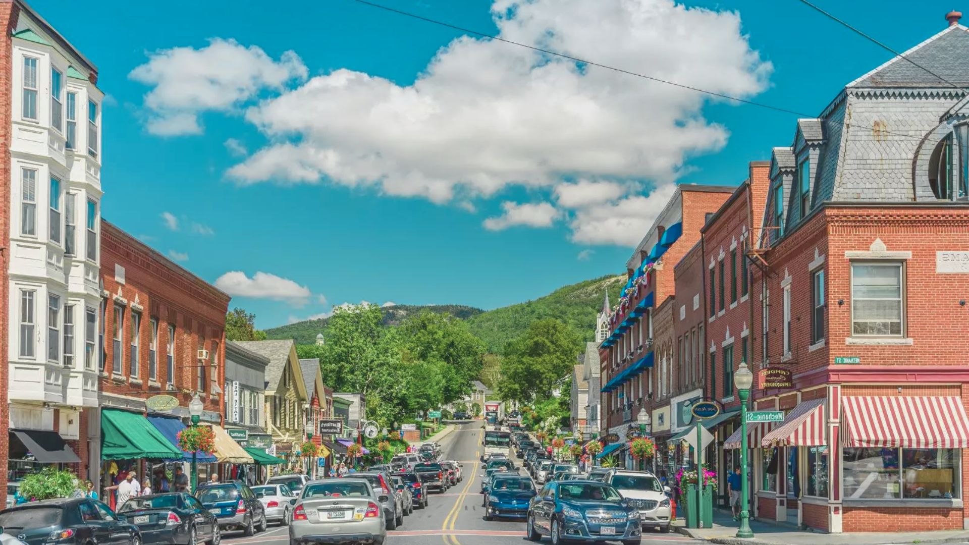 A city street lined with parked cars on both sides, showcasing urban life and traffic patterns.