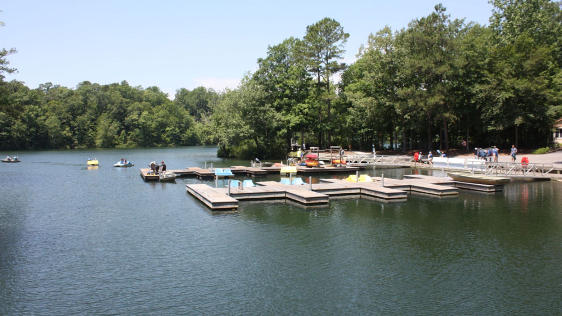 A picturesque lake with various boats and docks, surrounded by lush greenery.