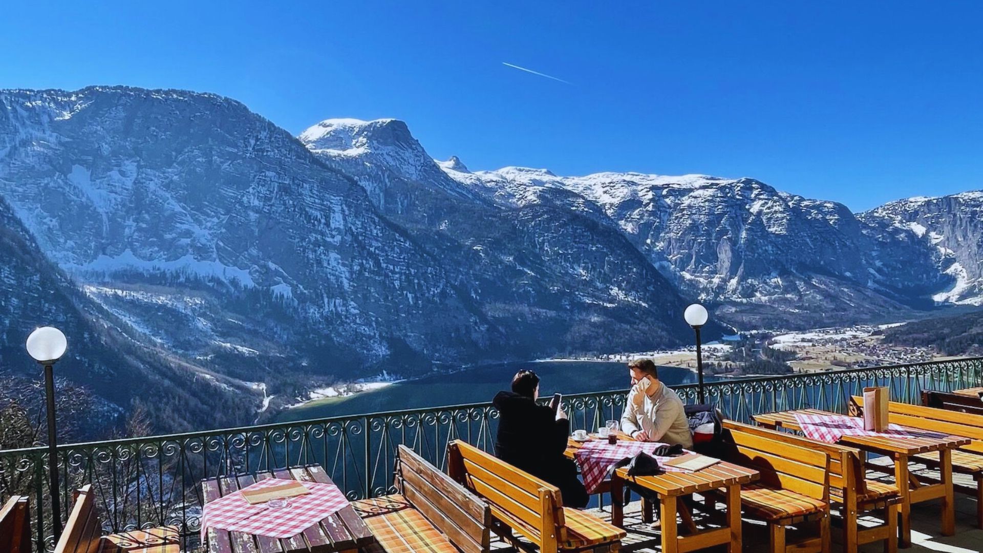 People seated at tables with a scenic view of mountains in the background.