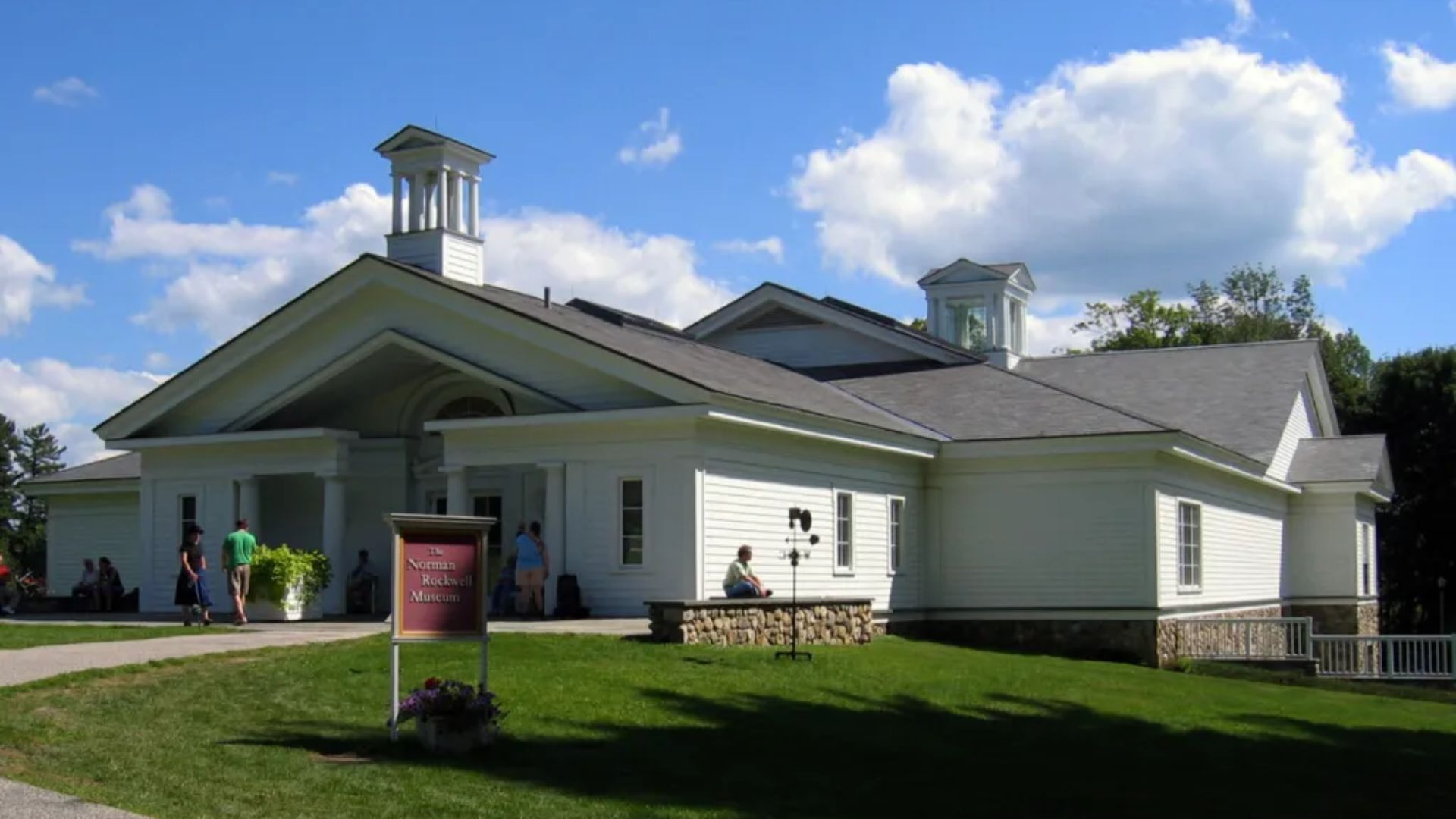 A white building featuring a prominent steeple atop its roof against a clear sky.
